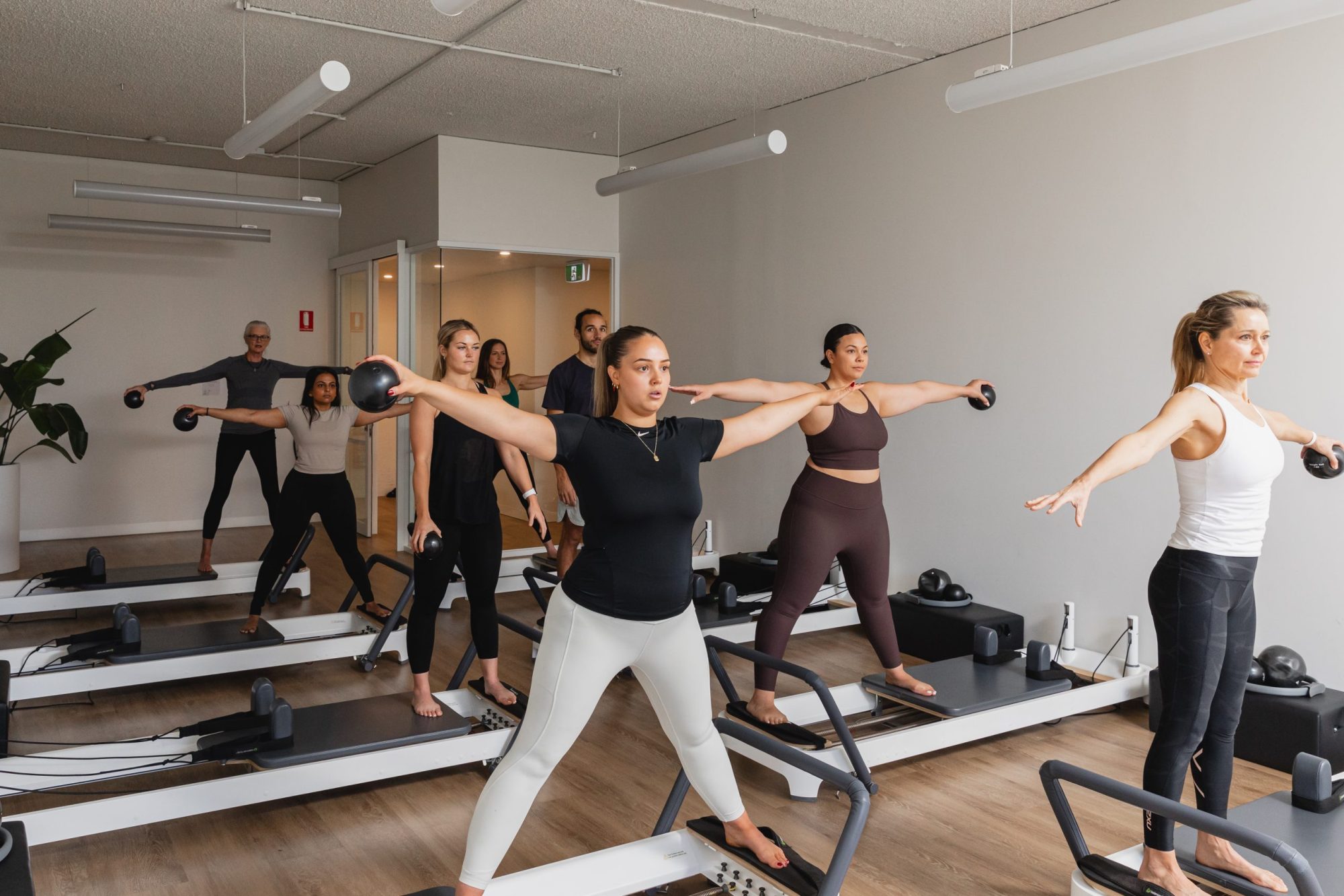 A full reformer Pilates class at All for One, everyone working through the same movement together